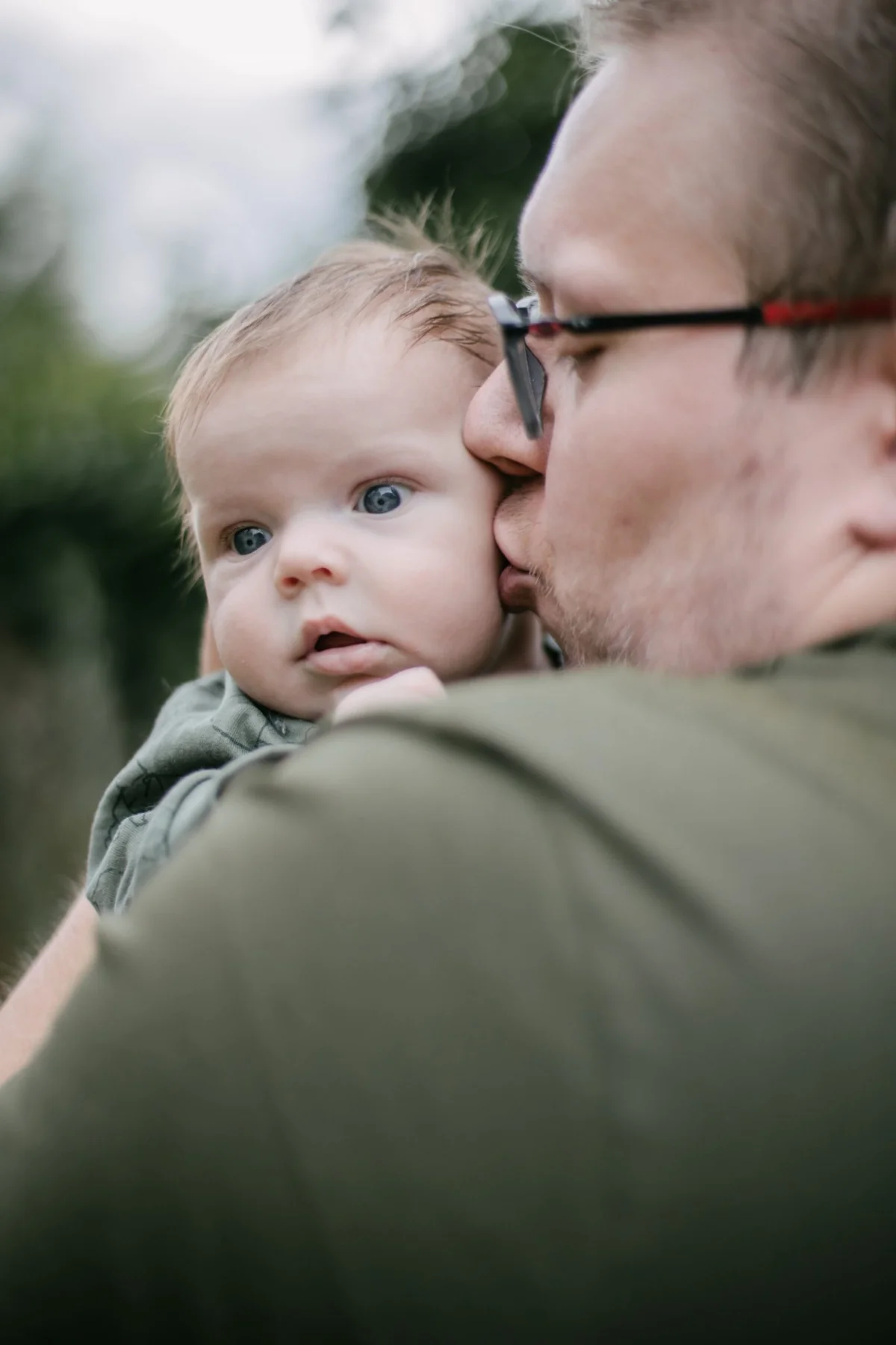 Vater hält sein Baby auf dem Arm und küsst es auf die Wange