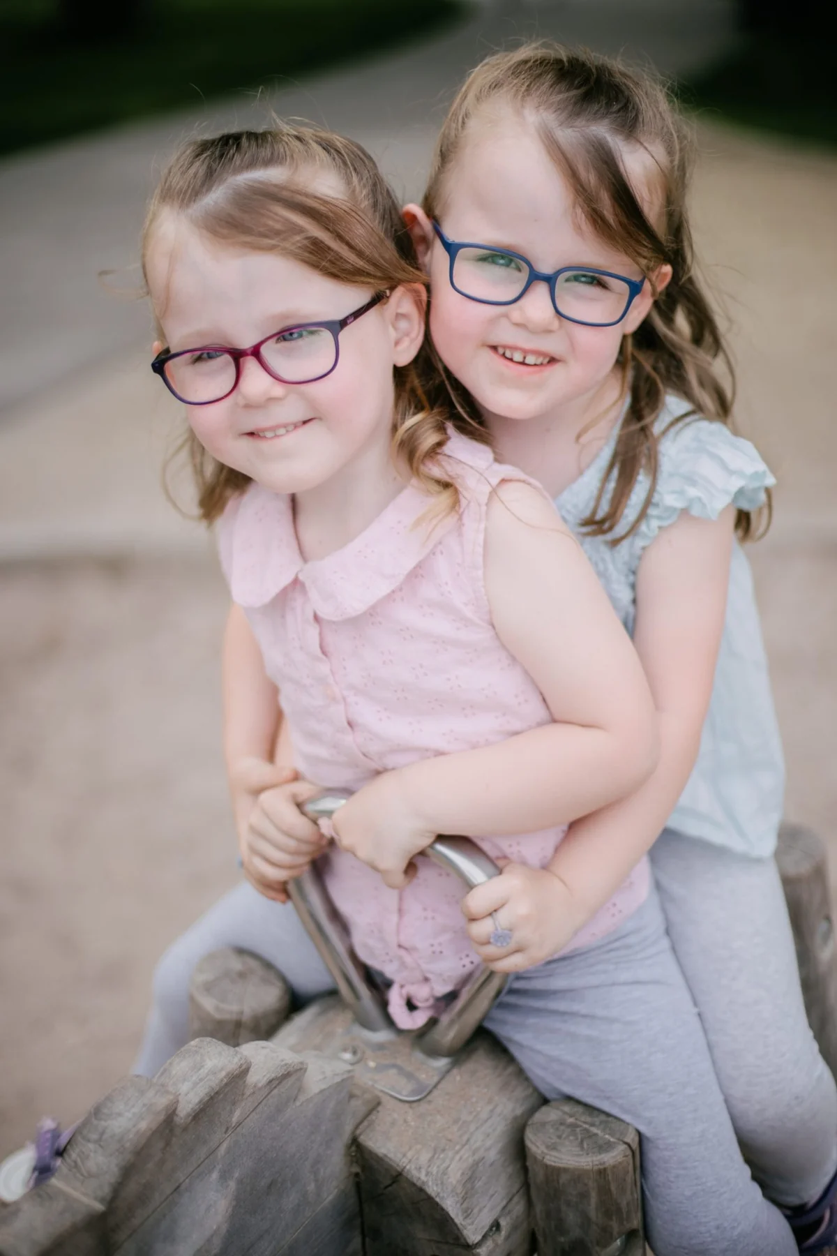 Zwei Kinder mit Brille sitzen gemeinsam auf einem Spielgerät