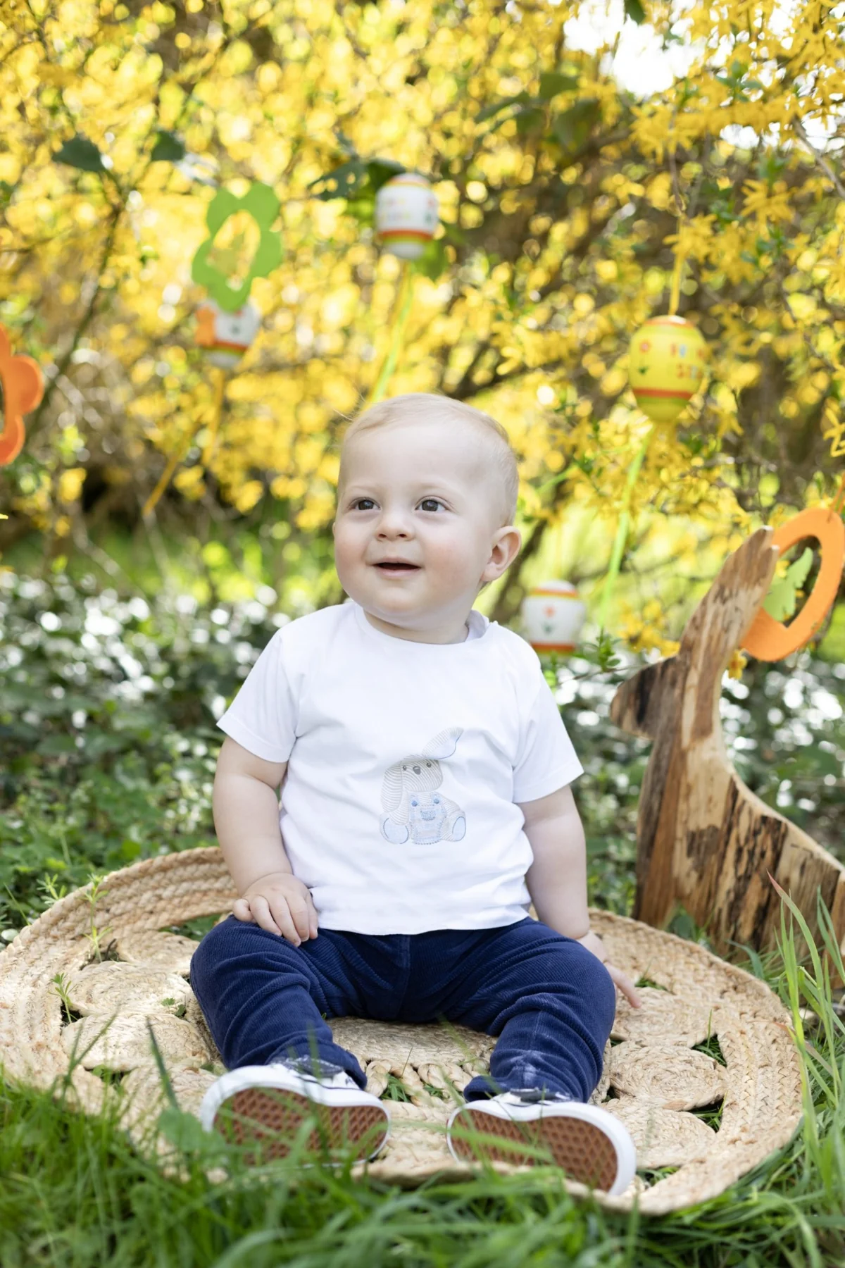 Kleinkind sitzt auf einem runden Teppich im Frühlingsgarten